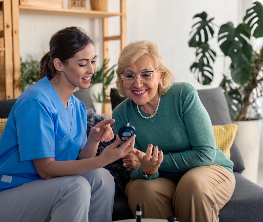 Caregiver assists elderly woman with medication at home.